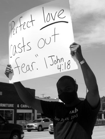 Micheal Johnson holds a sign in a peaceful protest down Main Street (photo credits to Christine Johnson).